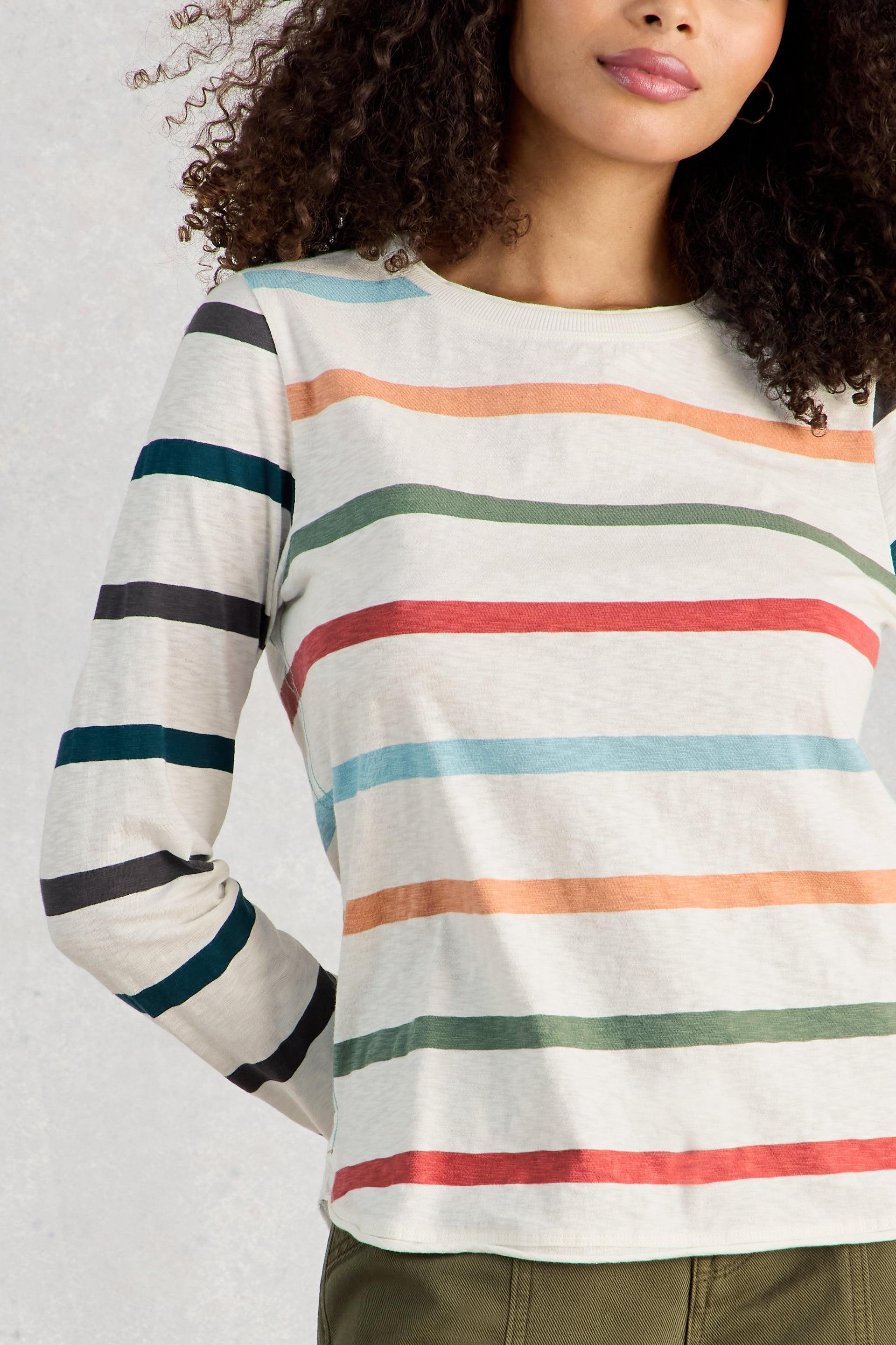 Woman wearing a colorful striped long-sleeve shirt against a light background