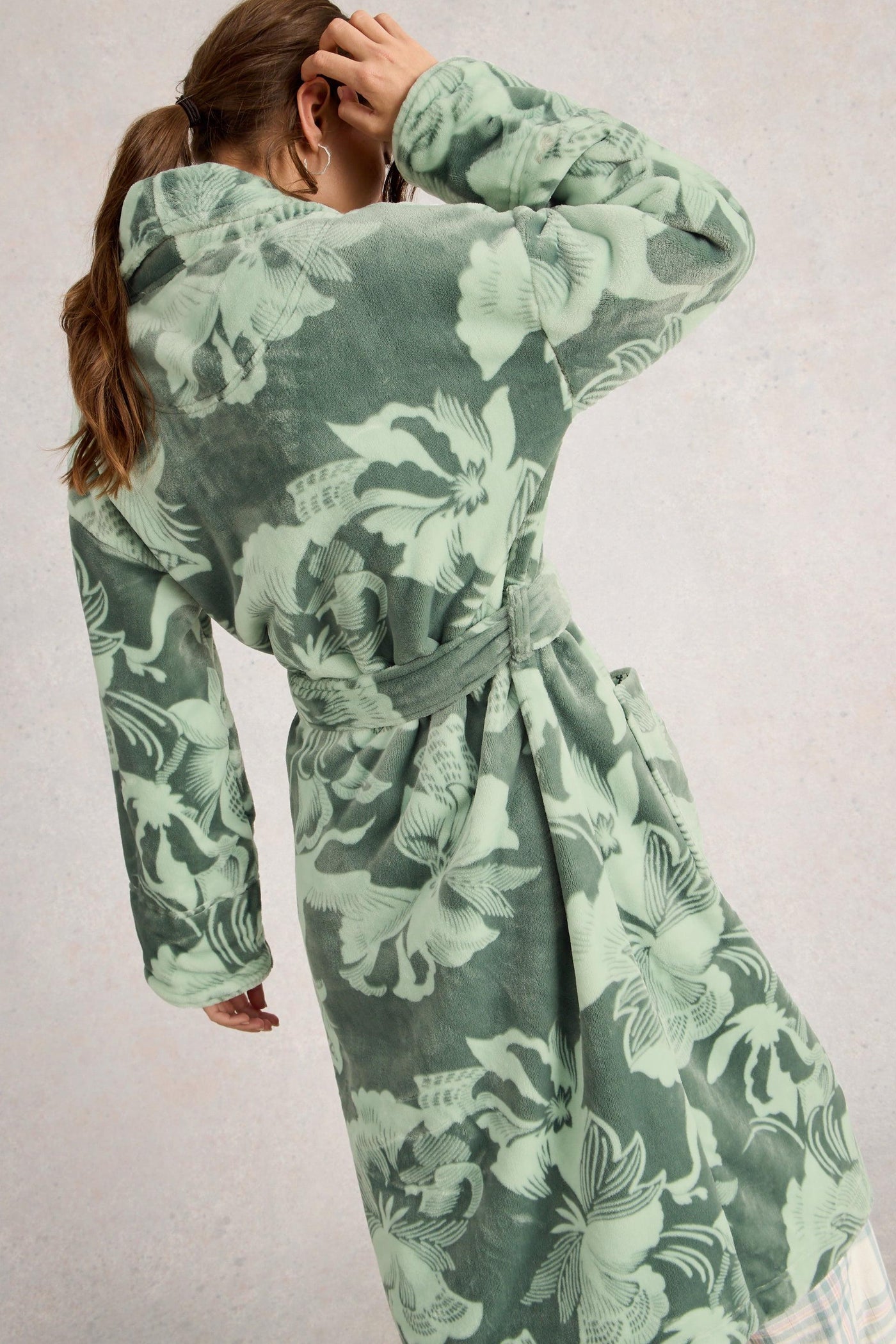 Green floral dressing gown worn by a person on a plain background