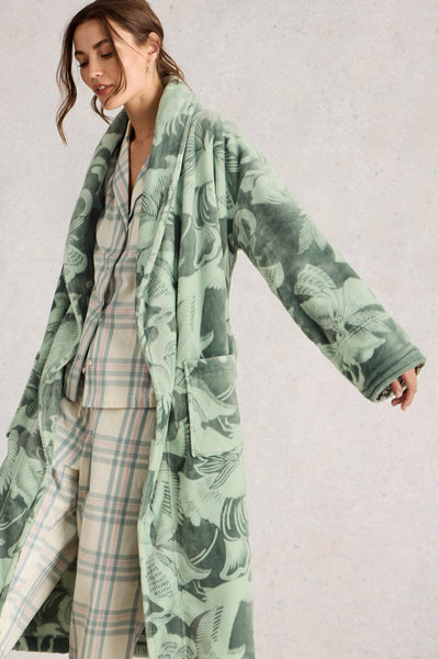 Woman wearing a green patterned dressing gown over a plaid outfit on a light gray background