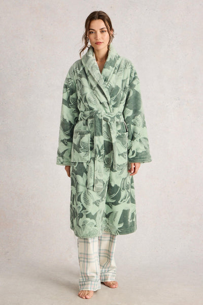 Woman wearing a green floral robe and matching pajama pants on a plain background