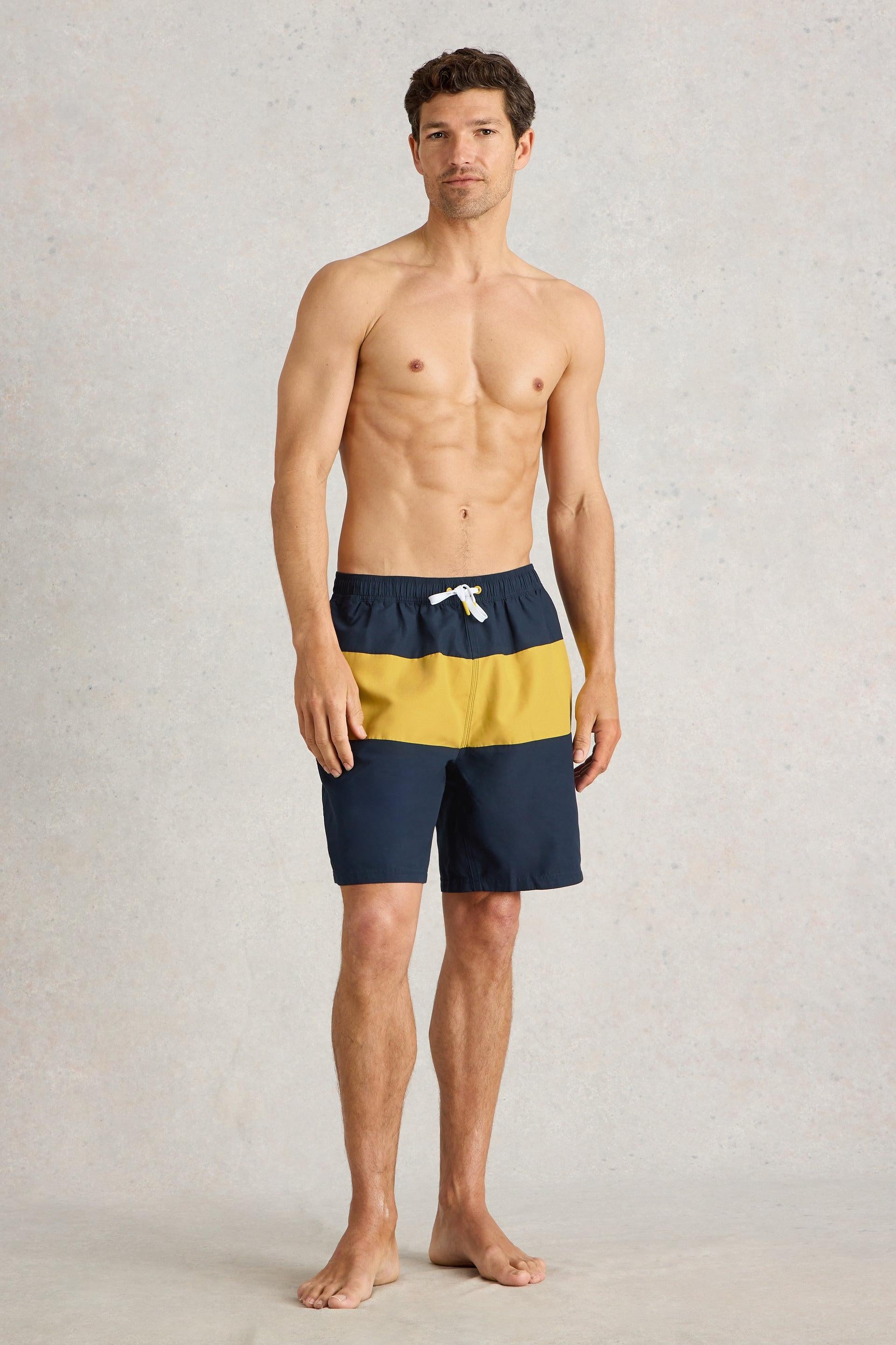 Model wearing navy and yellow colourblock beach shorts.