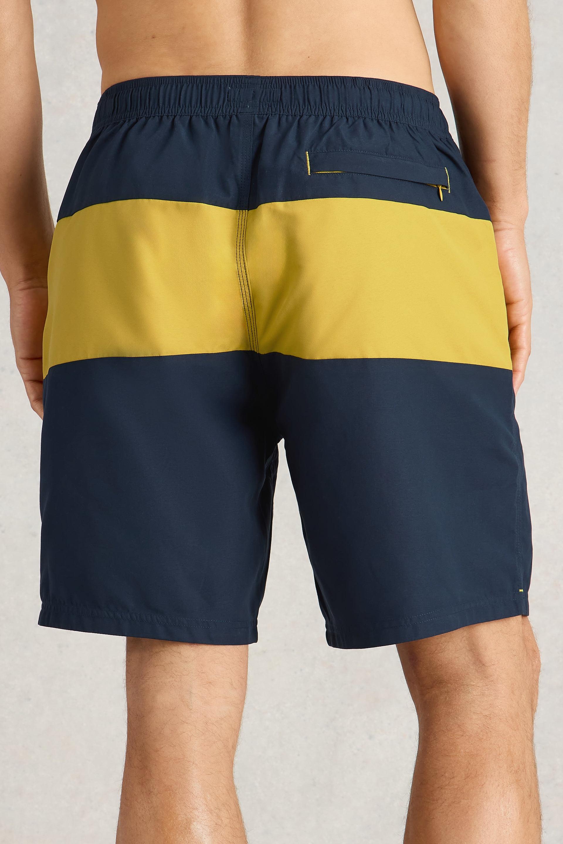 Close up of back of navy and yellow colourblock beach shorts showing a pocket.