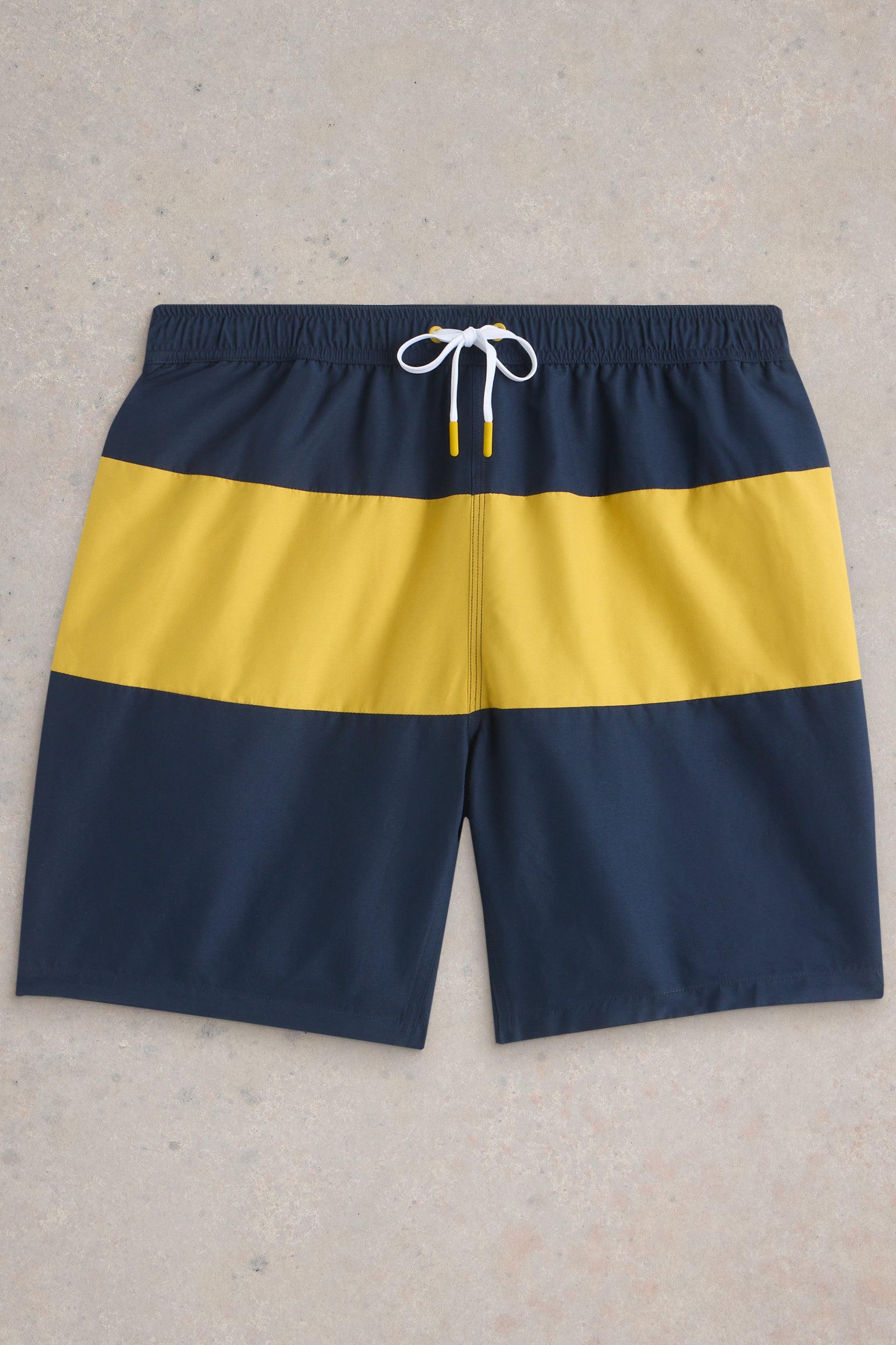 Navy and yellow colourblock shorts laid flat on neutral background.