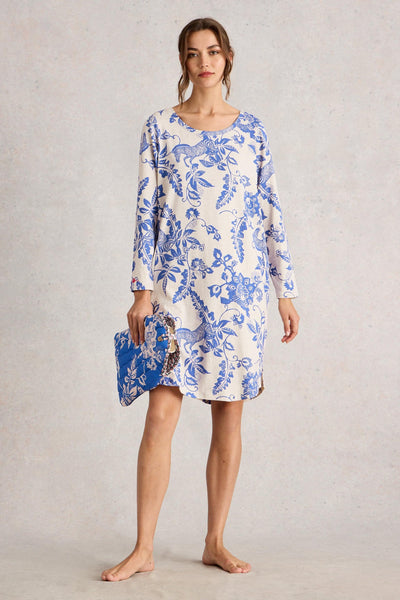 Woman wearing a floral organic cotton night dress holding a matching hot water bottle