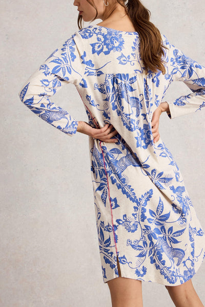 Woman wearing a blue and white floral night dress on a plain background