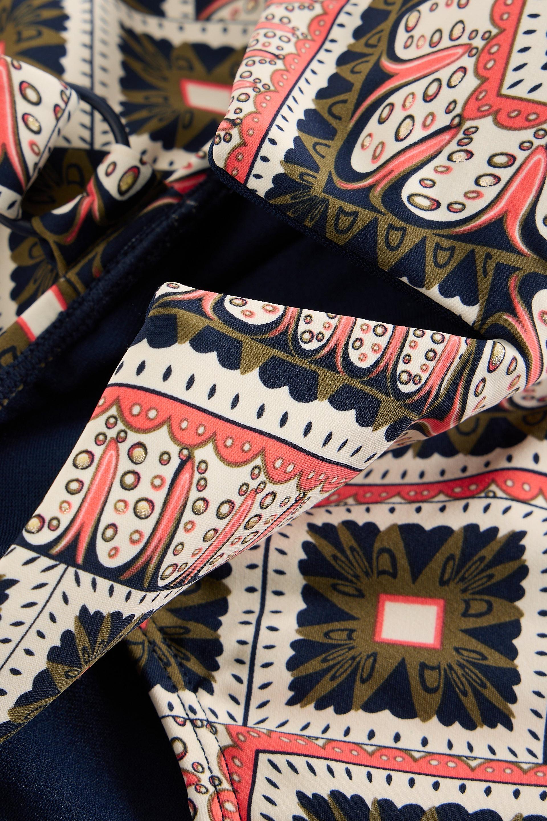 Close-up of patterned fabric with red, blue, and white design on a dark background