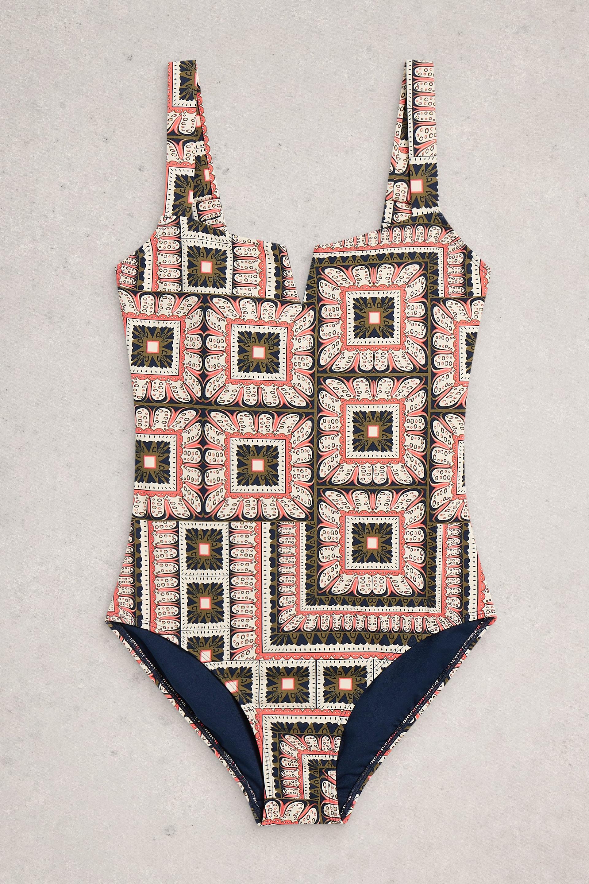 One-piece swimsuit with geometric pattern and navy accents on a light gray background