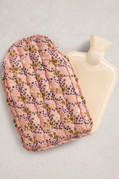 Hot water bottle with floral cover on a light gray background