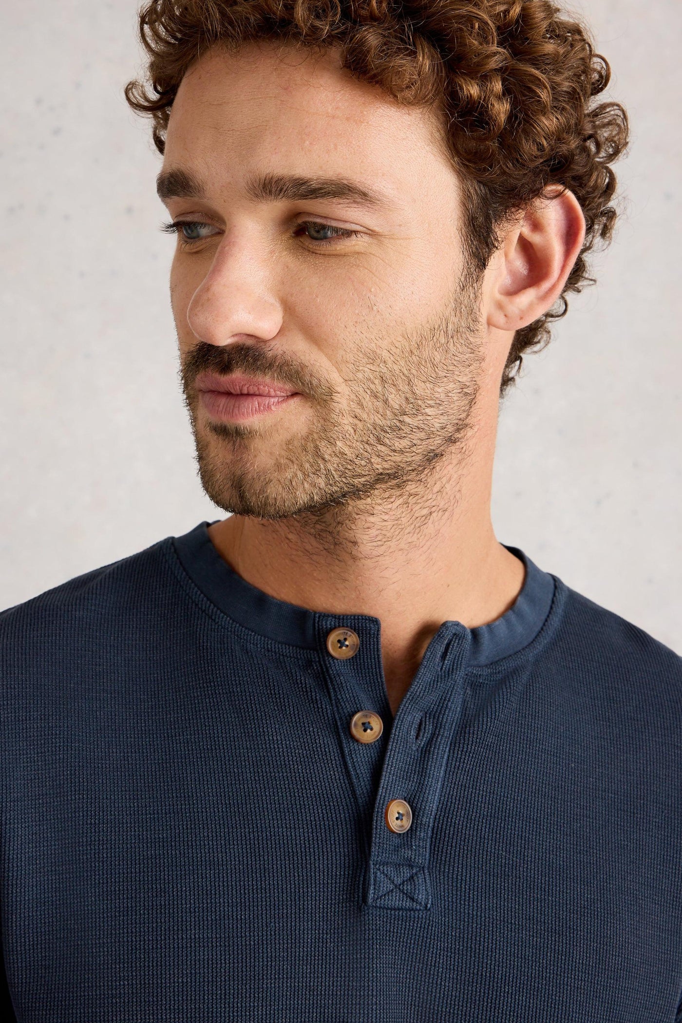 Man wearing a navy blue organic cotton shirt with wooden buttons against a light gray background