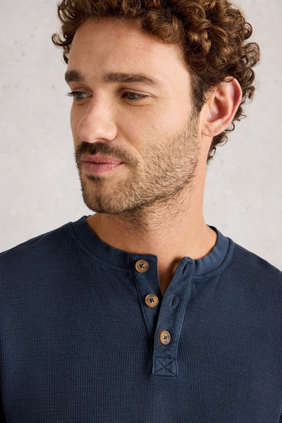 Man wearing a navy blue organic cotton shirt with wooden buttons against a light gray background
