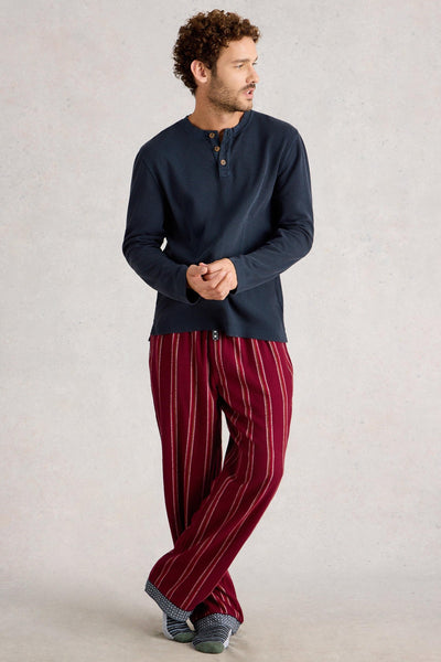Man wearing a navy long-sleeve organic cotton shirt and red striped pants on a light gray background