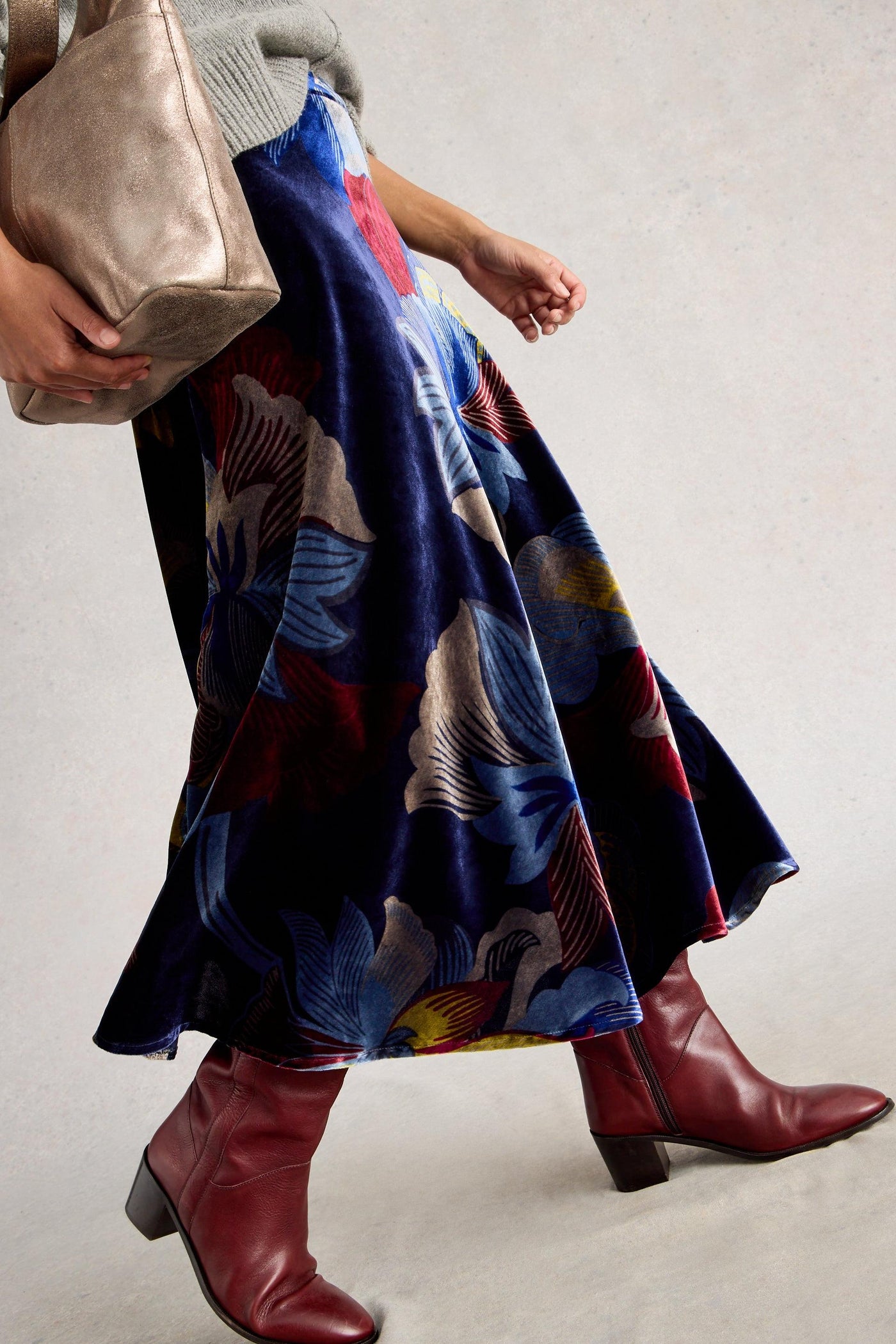 Person wearing a colorful skirt and red boots on a plain background