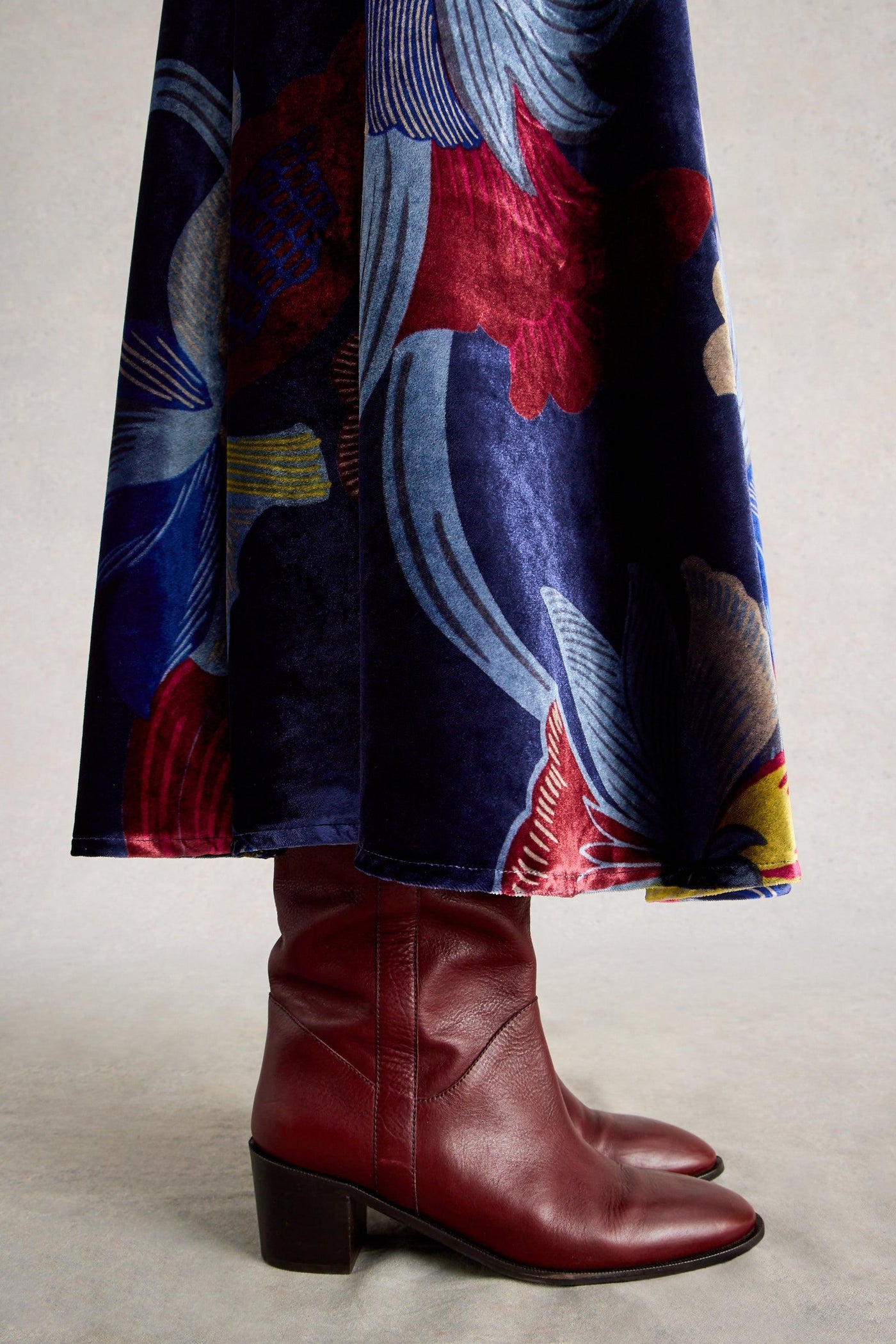 Colorful coat with abstract patterns and red boots on a neutral background
