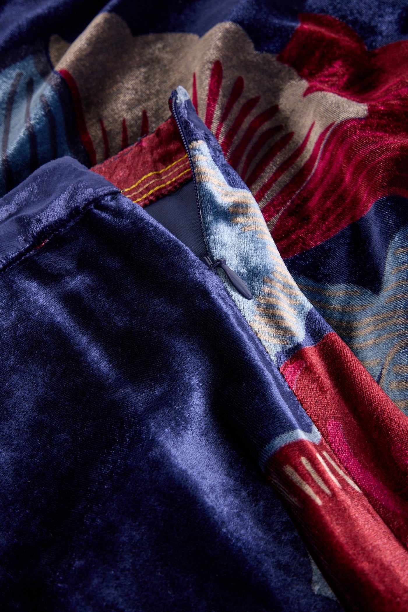 Stack of colorful fabric with patterns including red, blue, and beige.