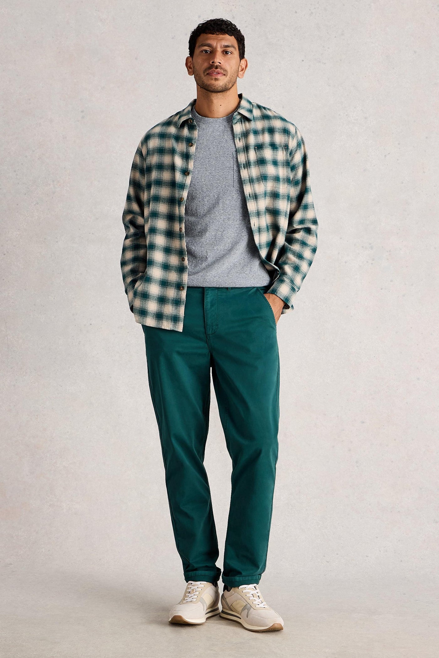 Man wearing organic cotton grey t-shirt, styled with checkered shirt and dark green trousers and white sneakers