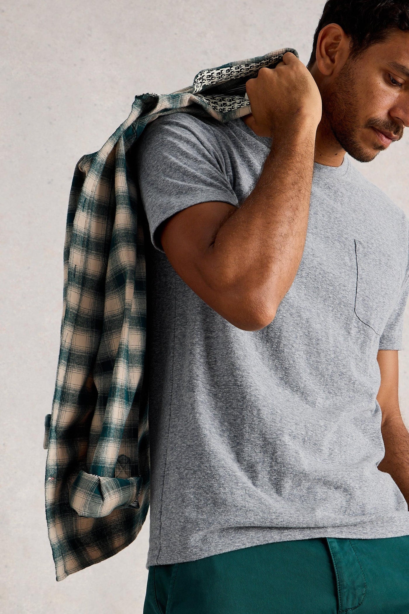 Man wearing grey organic cotton t-shirt holding a shacket over his shoulder