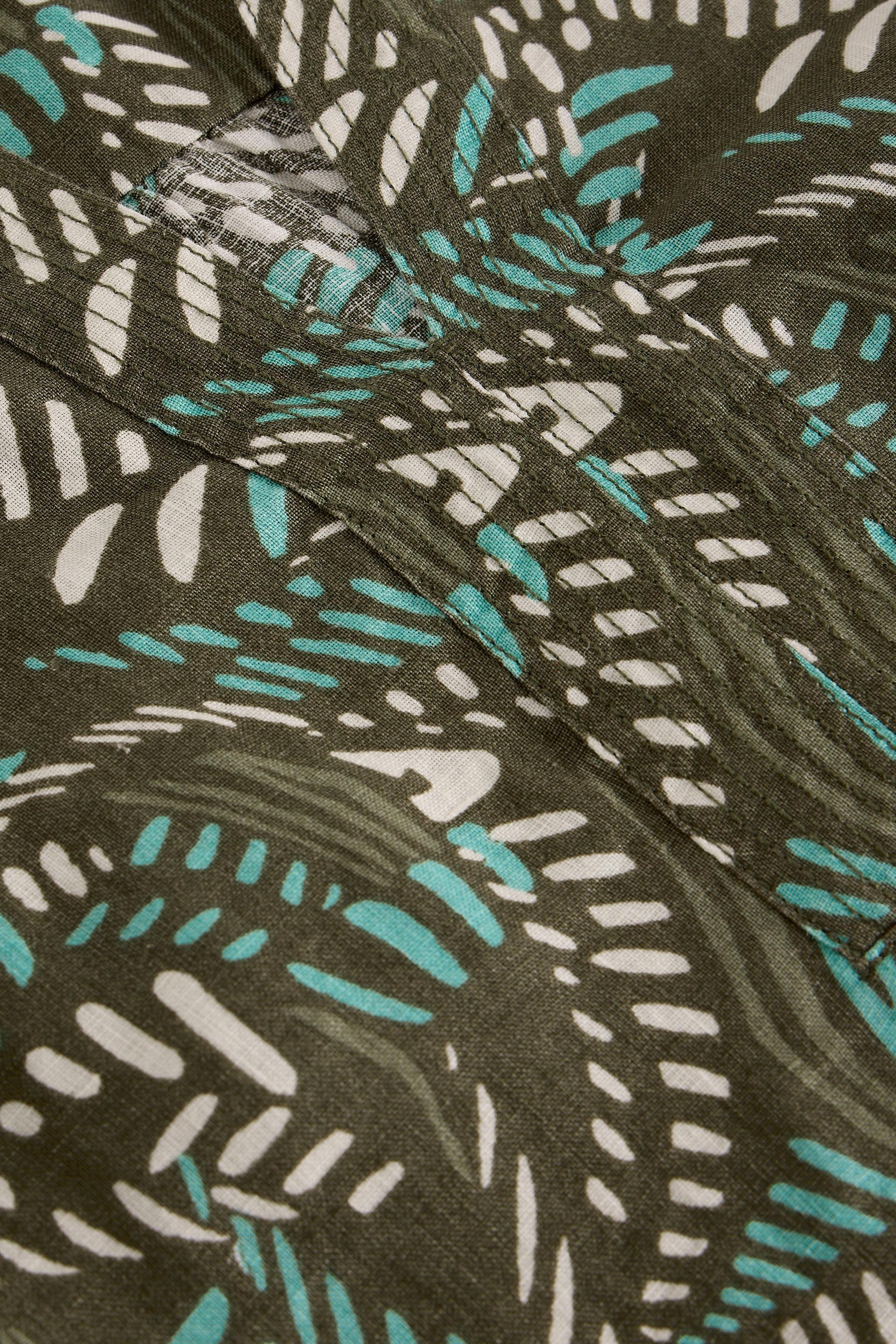 Close-up of linen fabric with a leaf pattern in green, white, and brown.