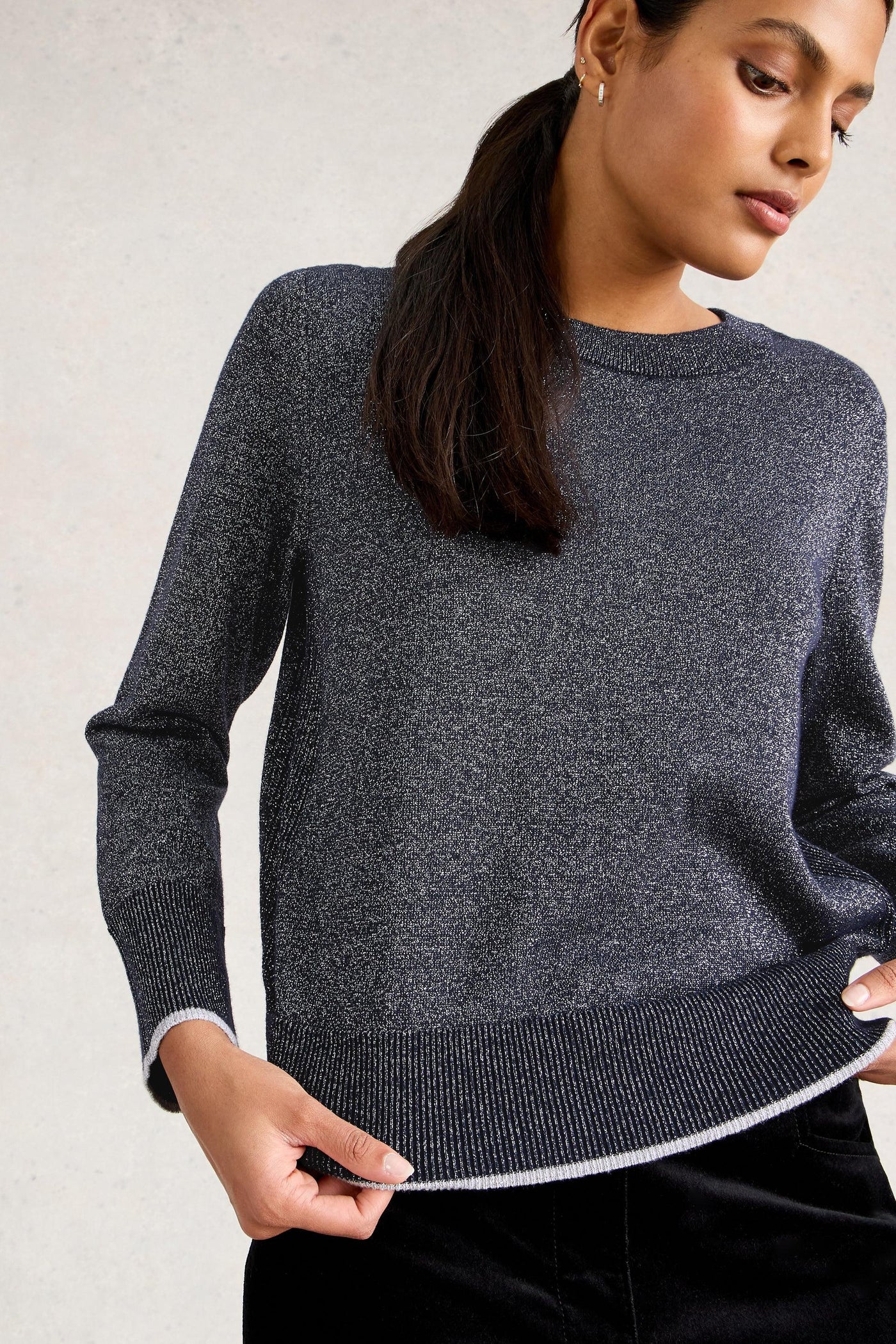 Woman wearing a dark gray organic cotton sweater against a light background
