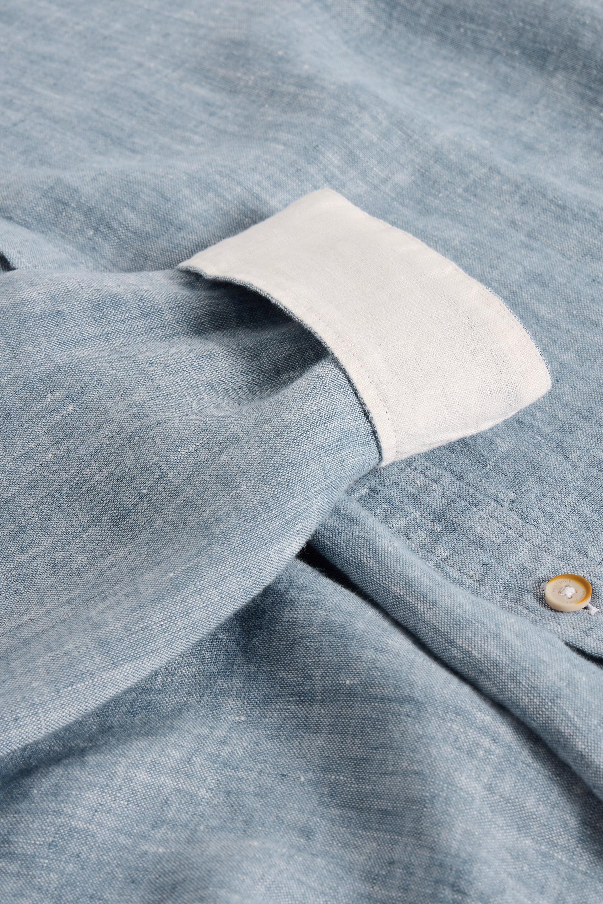 Close-up of a blue shirt with a white cuff and button detail