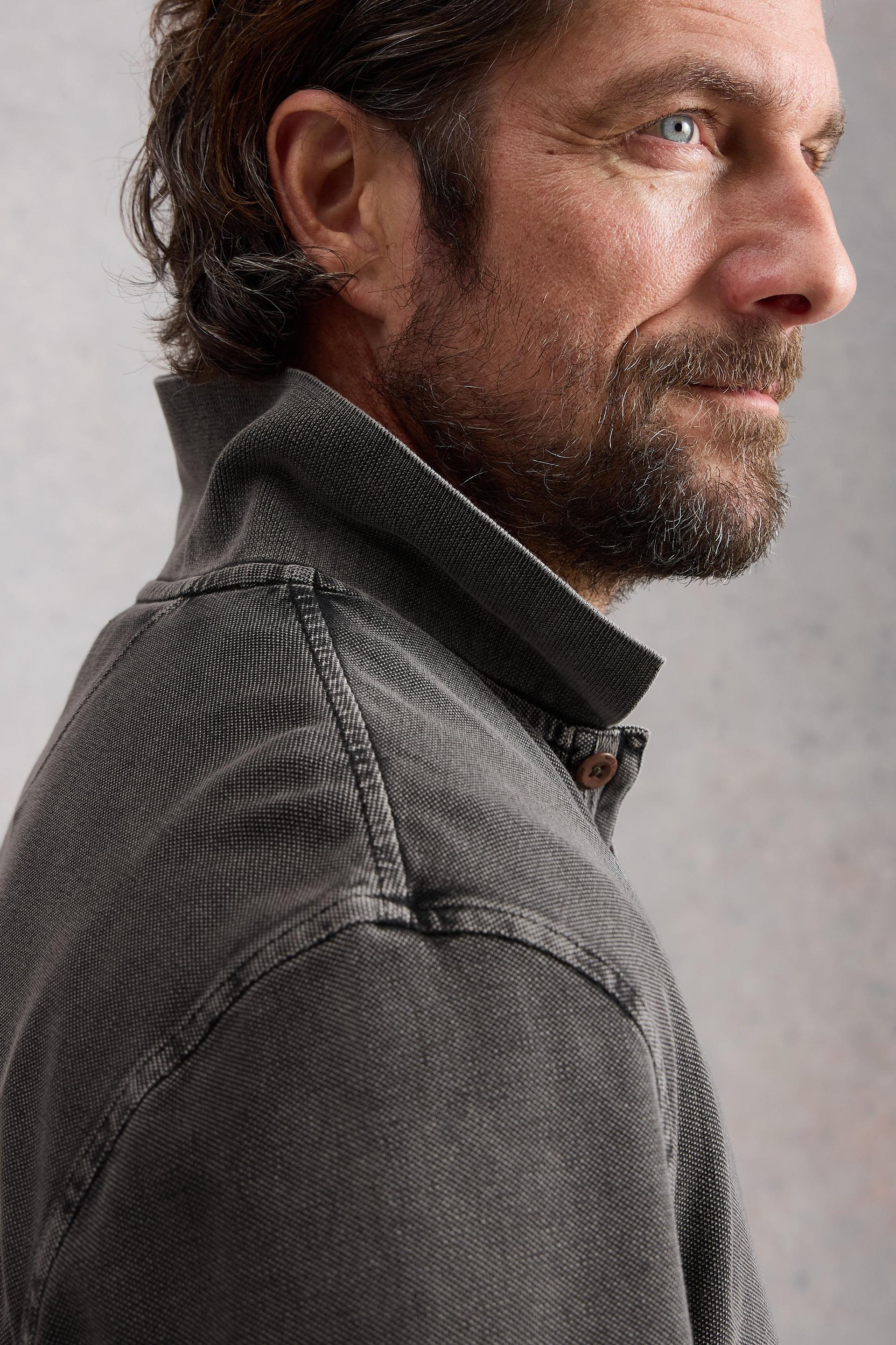 Man wearing a washed black shirt against a neutral background