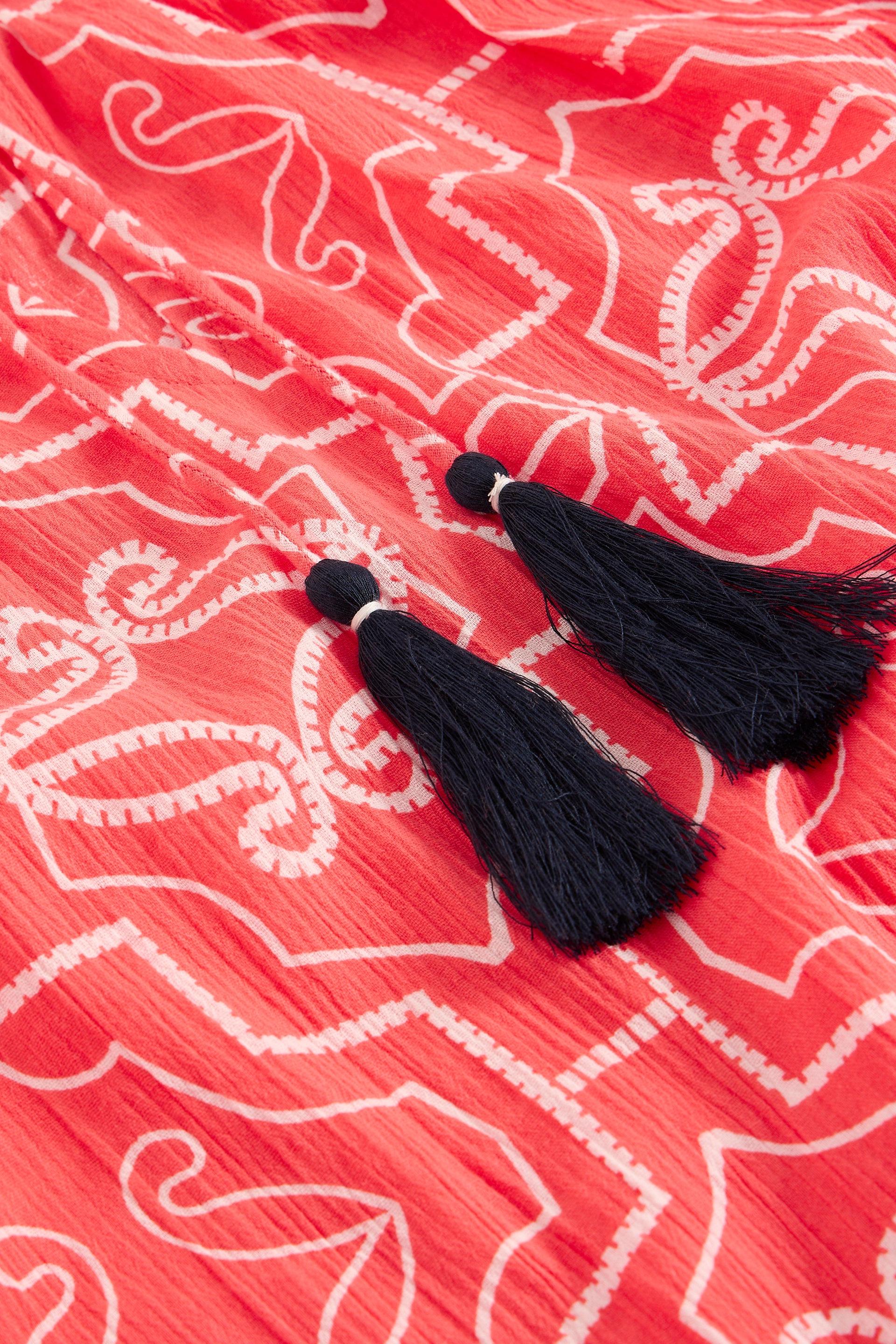 Black tassels on a red and white organic cotton beach cover up 