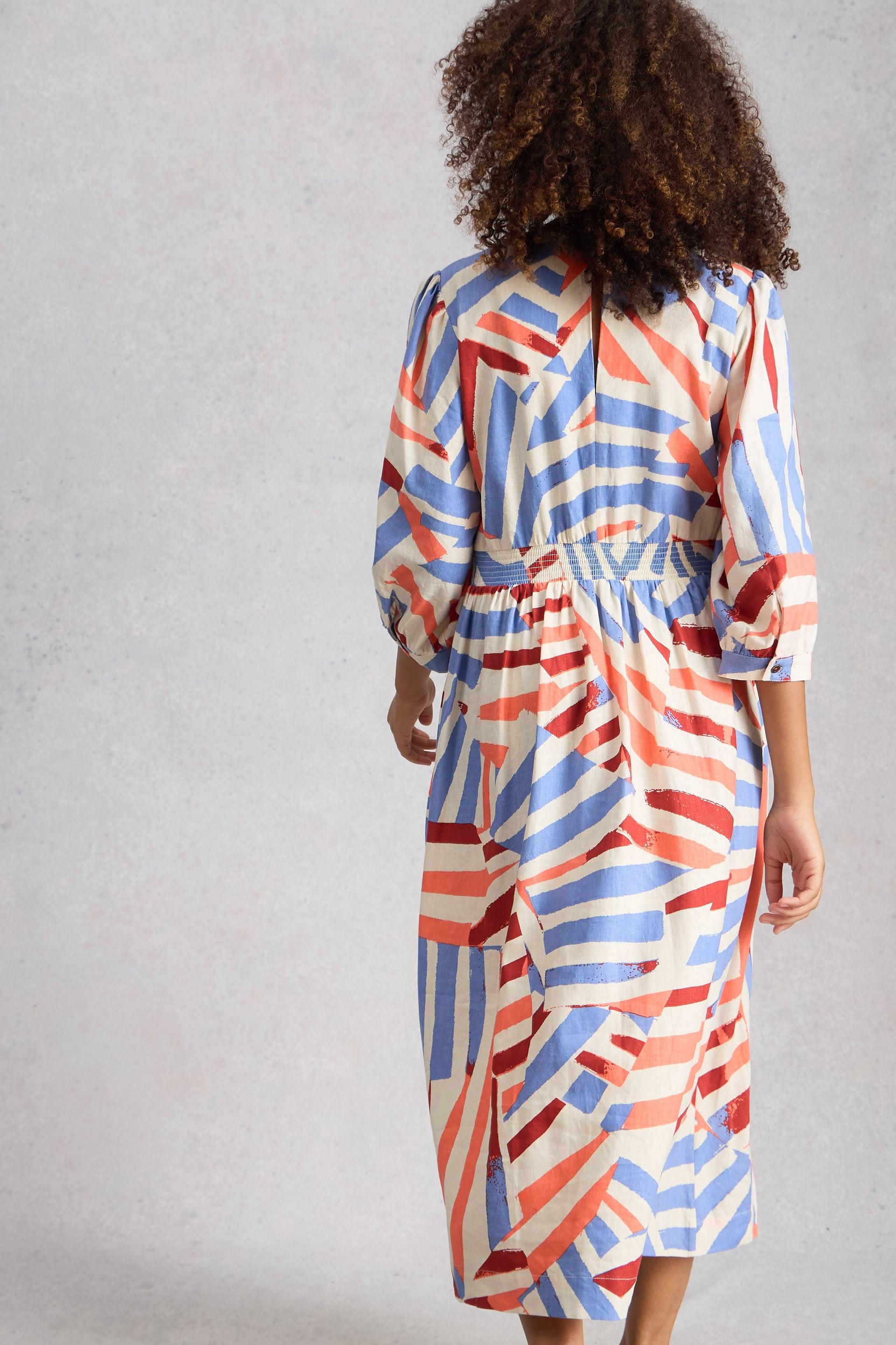 Person wearing a colorful geometric patterned dress against a plain background