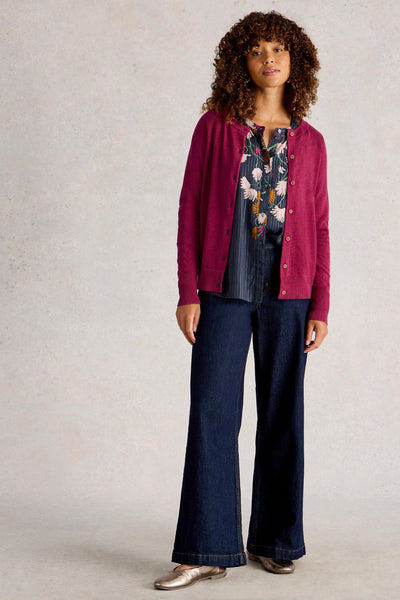 Woman wearing organic cotton plum cardigan, styled with wide-leg denim jeans, floral blouse and gold shoes