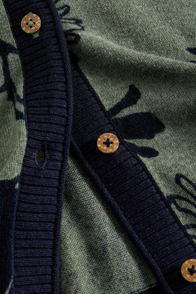 Close-up of the front of a green and navy floral cardigan showing wooden buttons and navy ribbed trim