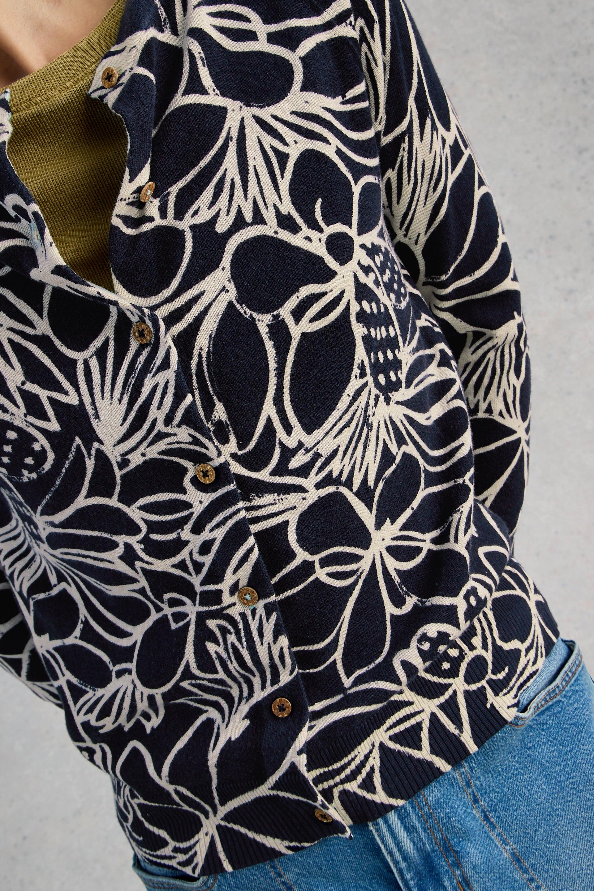 Navy organic cotton cardigan with white floral pattern worn by a person on a gray background