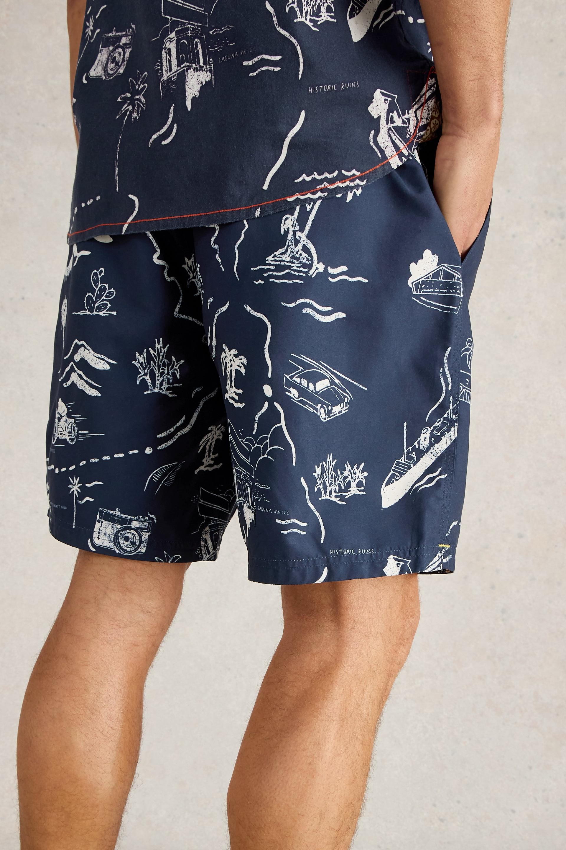 Back view of navy beach shorts with a tropical map print.