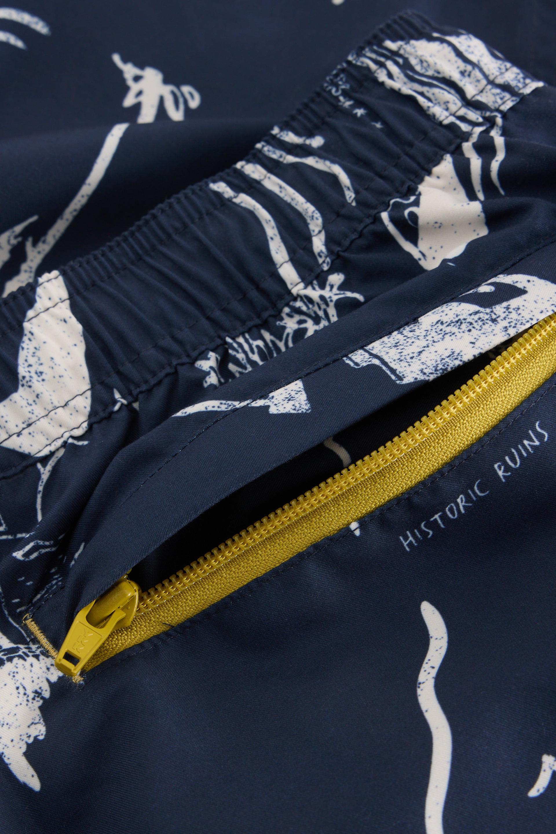 Close up of yellow zipped pocket on the back of mens navy beach shorts.