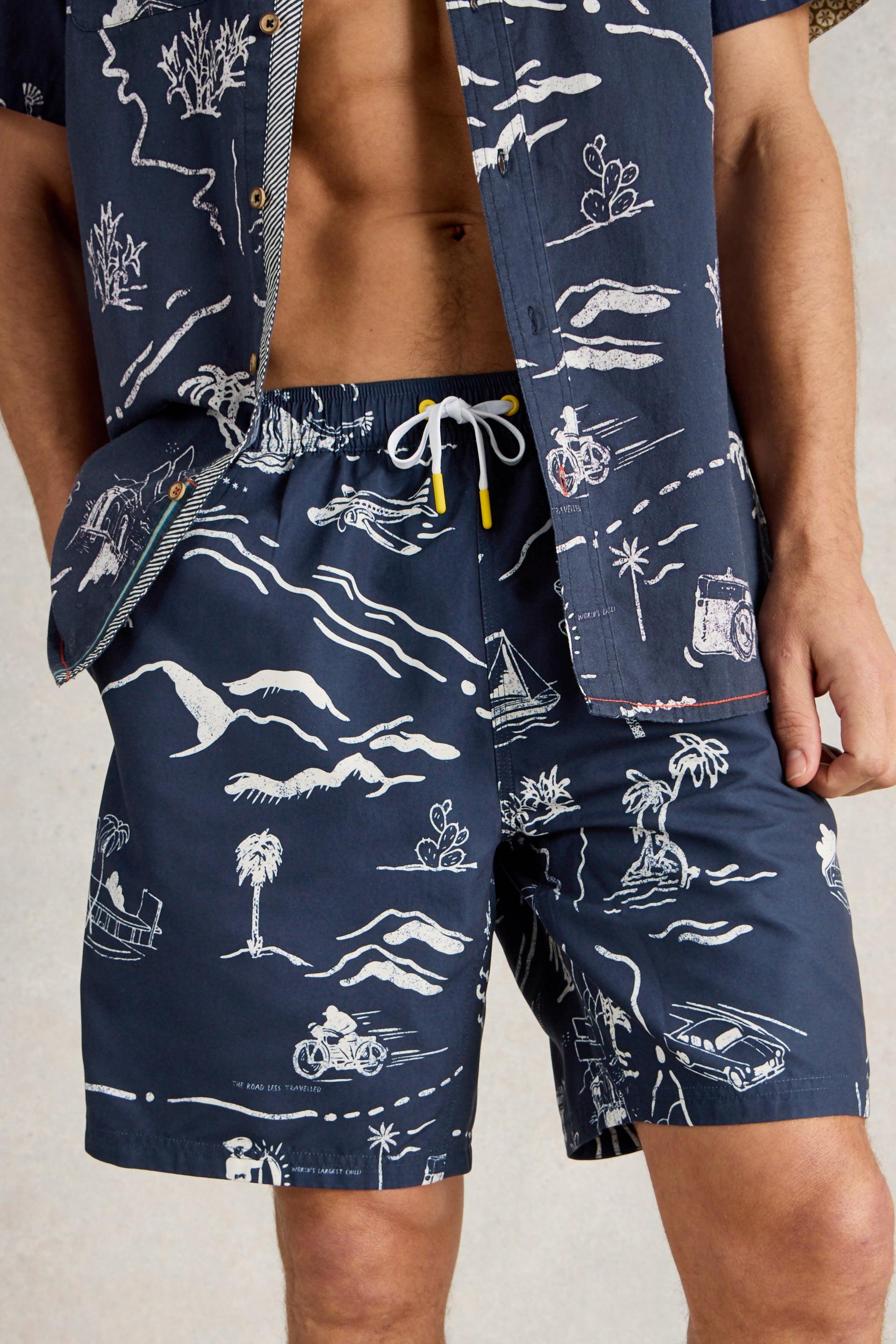 Model wearing navy beach shorts with a tropical map print and a white drawstring.