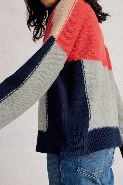 Colour-blocked wool sweater with red, blue, and gray sections worn by a person on a light background
