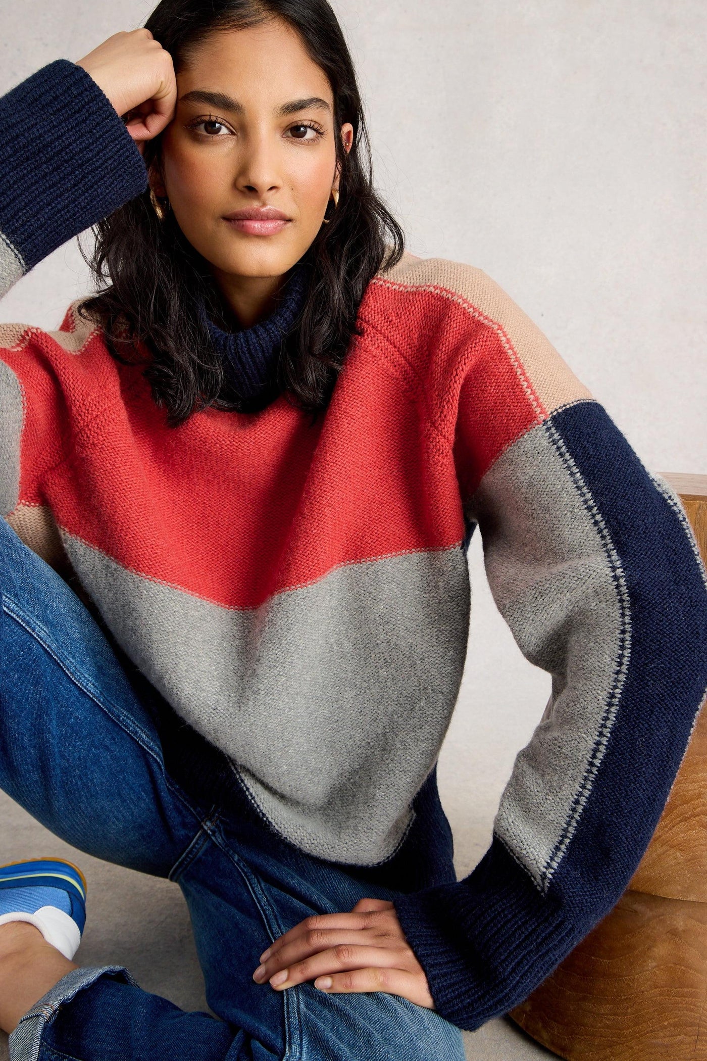Woman wearing a colourful wool and organic cotton sweater with red, gray, and navy sleeves.