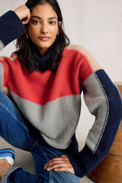 Woman wearing a colourful wool and organic cotton sweater with red, gray, and navy sleeves.