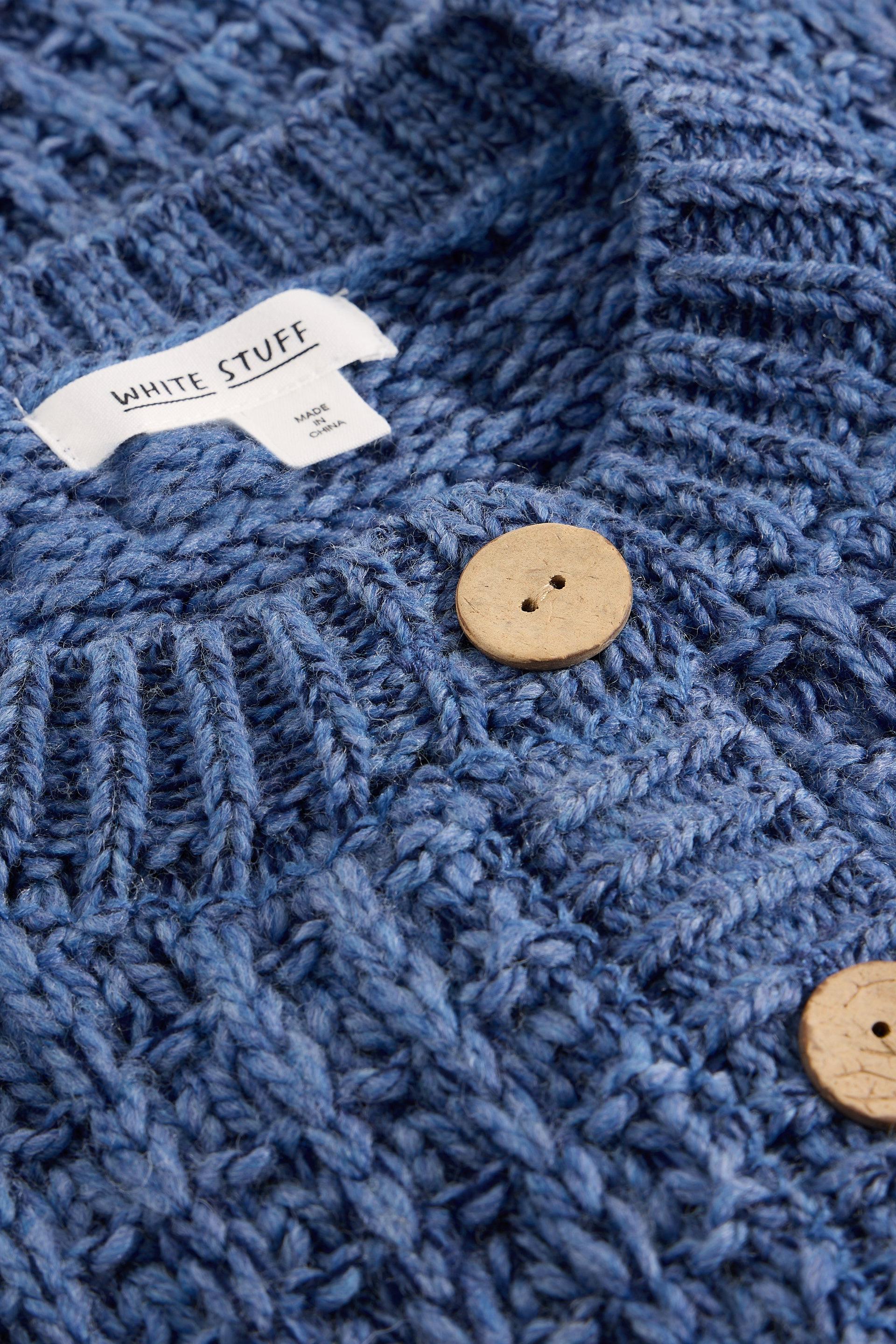 Close-up of a blue textured fabric with wooden buttons and a label, featuring the brand 'White Stuff'.
