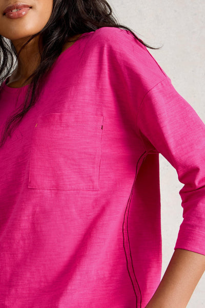 Close-up of a person wearing a bright pink long-sleeve top against a neutral background
