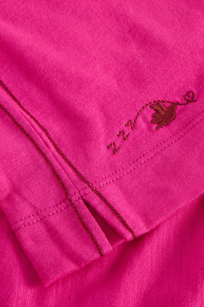 Close-up of a pink garment with a small embroidered design on a pink background
