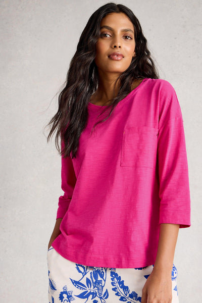 Woman wearing a bright pink organic cotton top with a neutral background