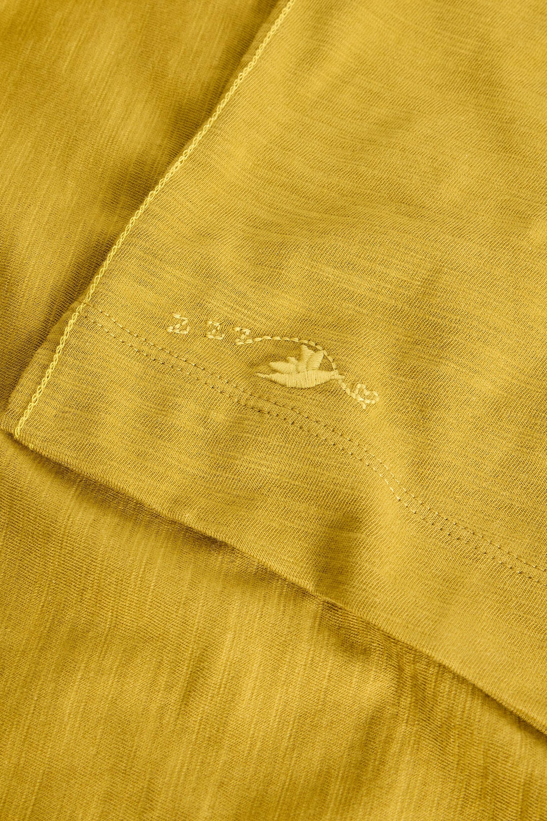 Close-up of a mustard yellow fabric with a small embroidered design.