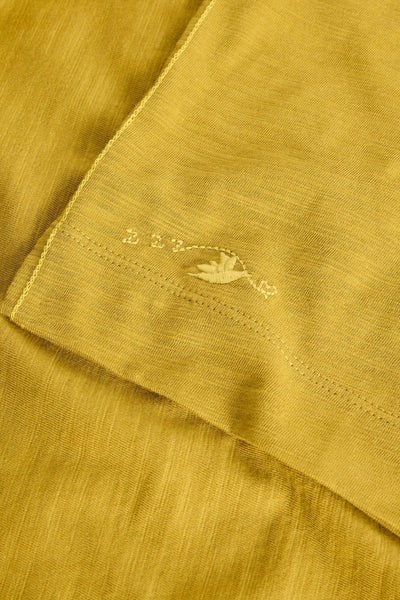 Close-up of a mustard yellow fabric with a small embroidered design.