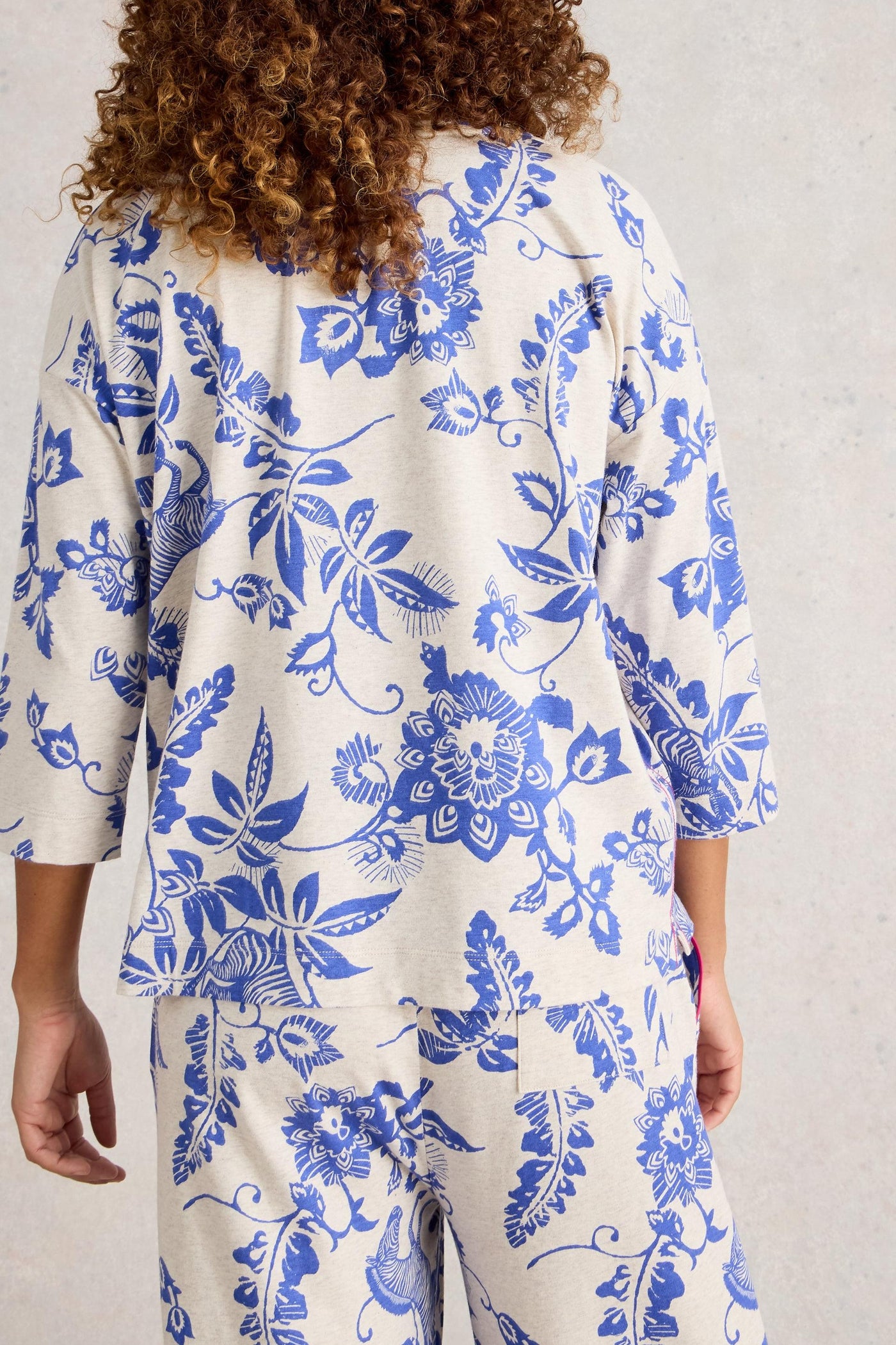 Person wearing blue floral patterned pyjamas on a plain background