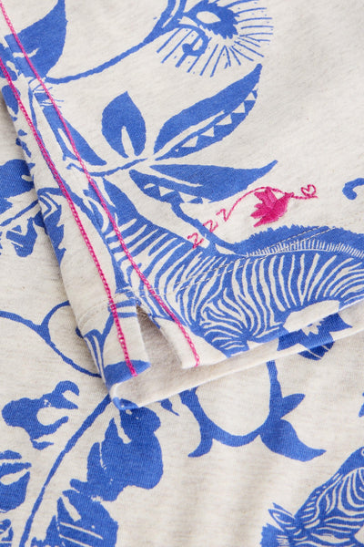 Close-up of organic cotton fabric with blue floral pattern and pink stitching on a white background