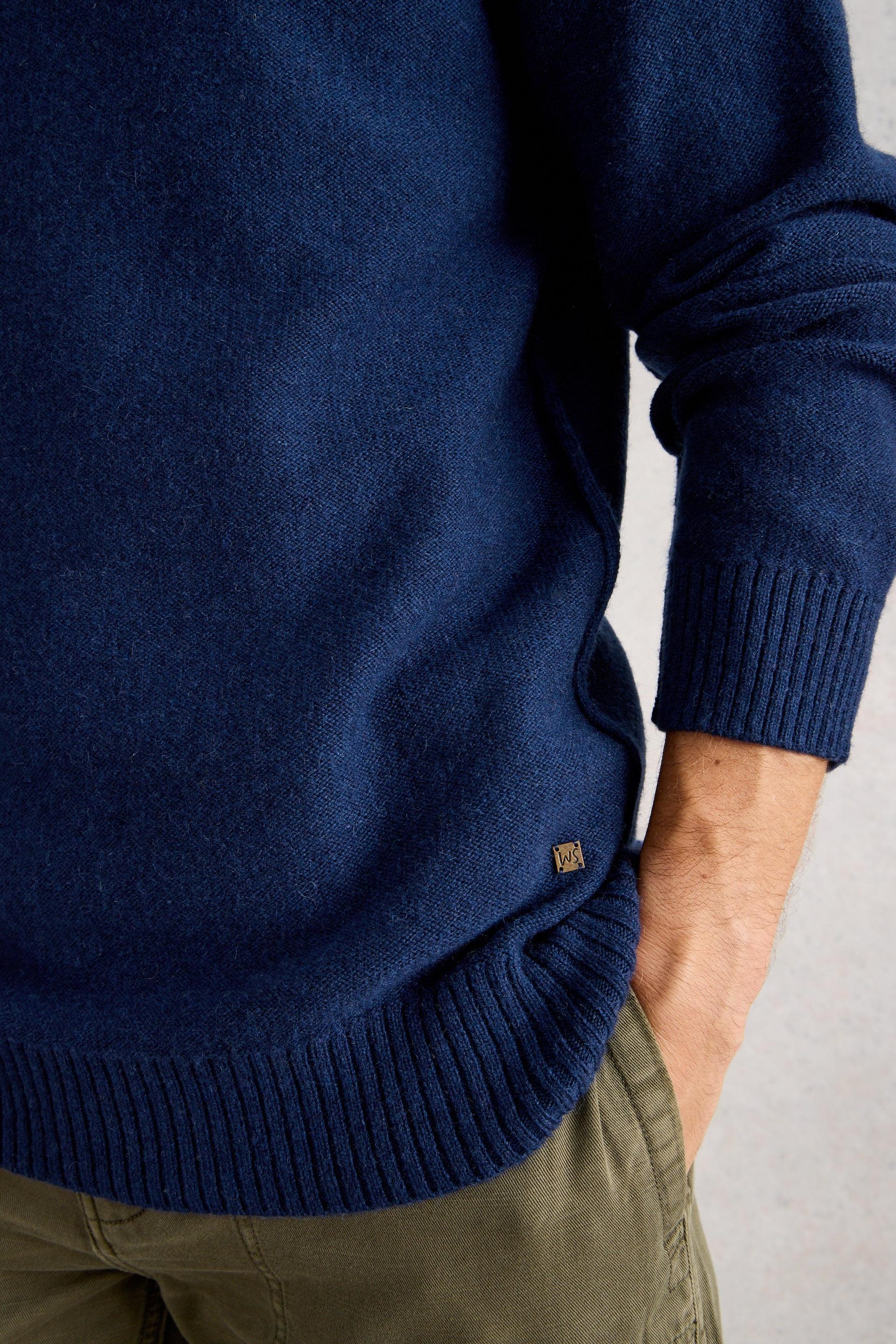 Navy blue wool sweater worn by a person on a light gray background