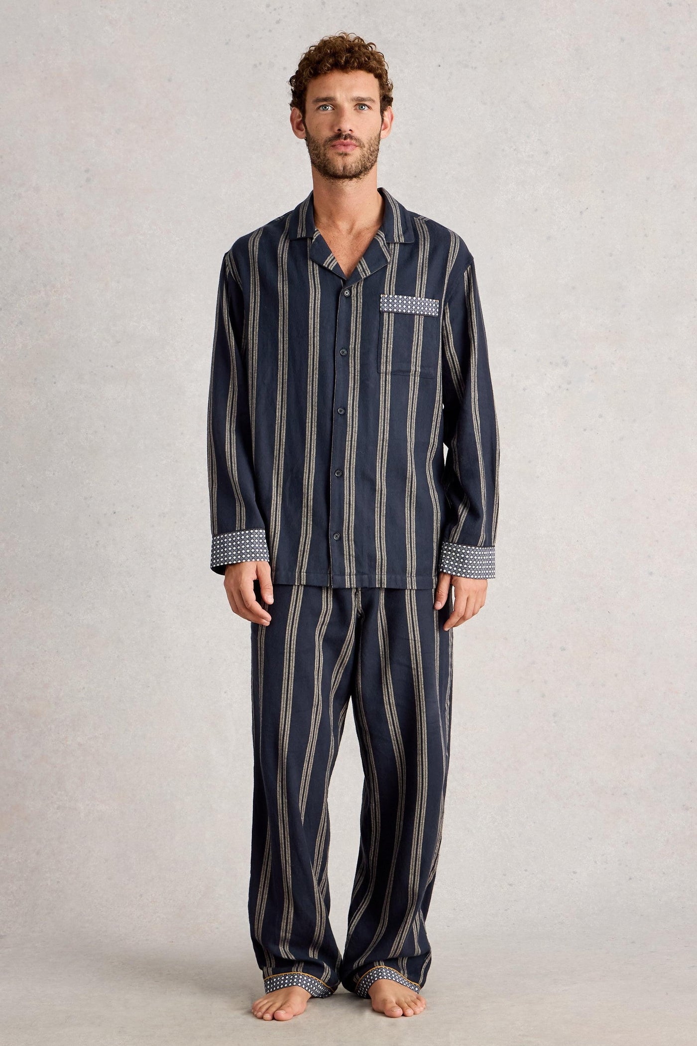 Man wearing a navy striped organic cotton pajama set on a plain background