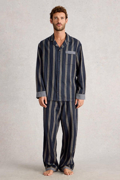 Man wearing a navy striped organic cotton pajama set on a plain background