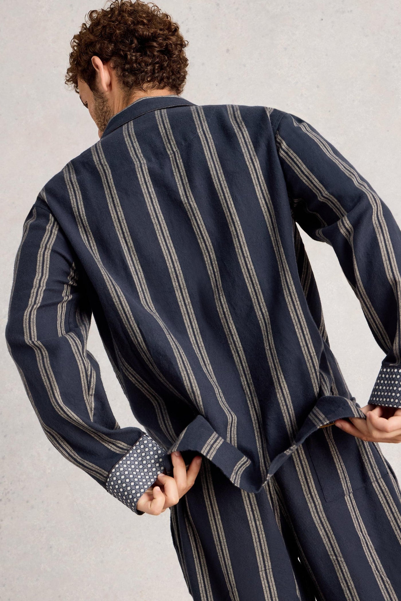 Man wearing navy and gray striped pyjamas against a plain background