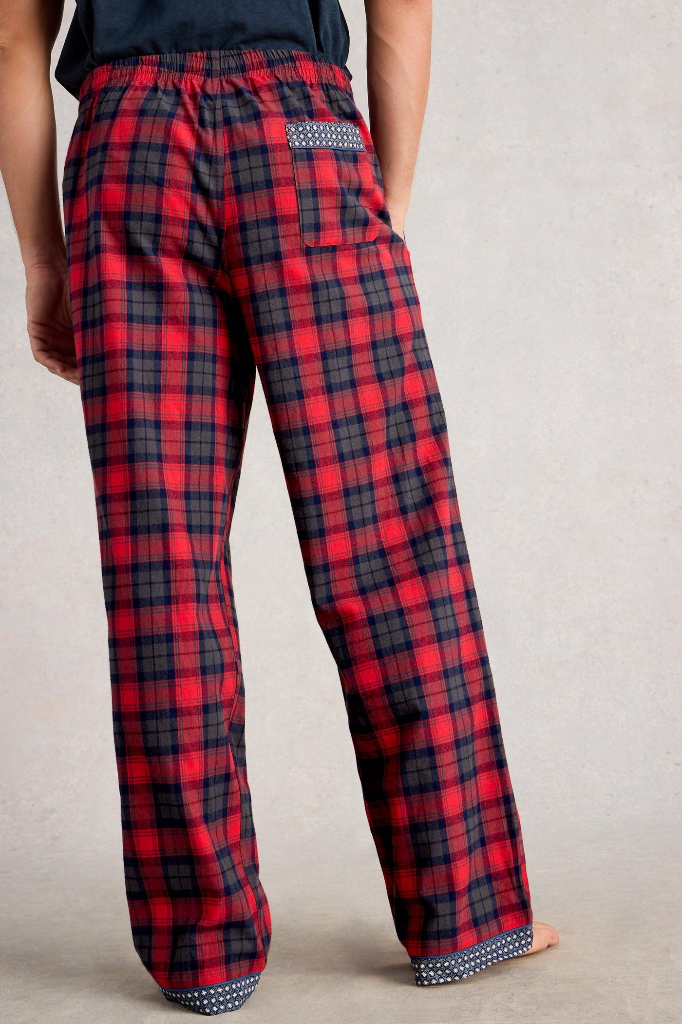 Red and black plaid pajama pants on a plain background