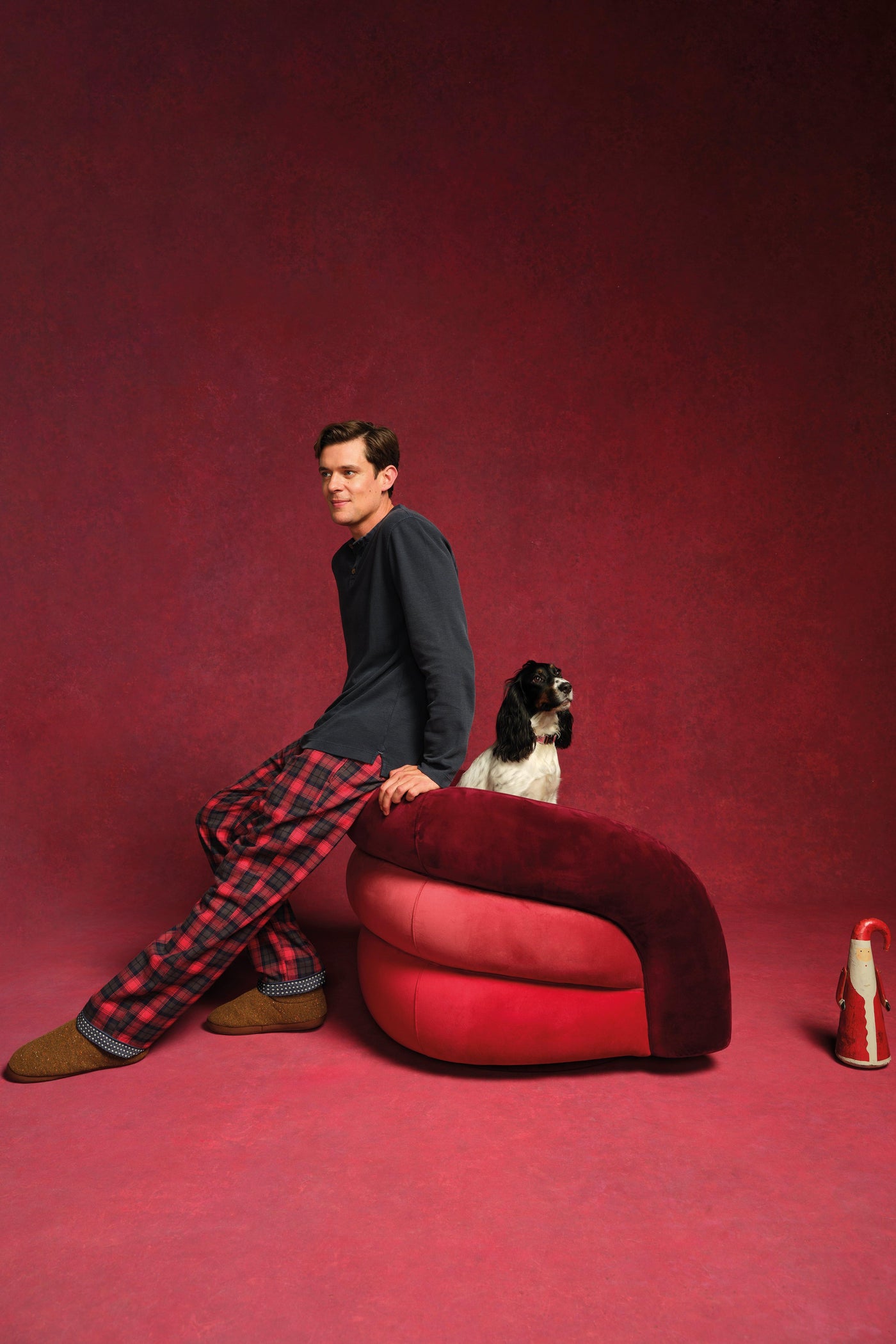 Man sitting on a red chair with a dog on a red background