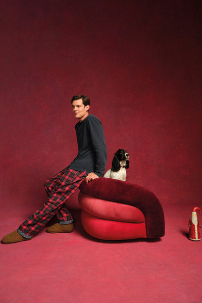 Man sitting on a red chair with a dog on a red background